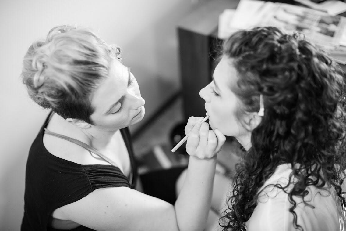 Olivia applying makeup to a bride